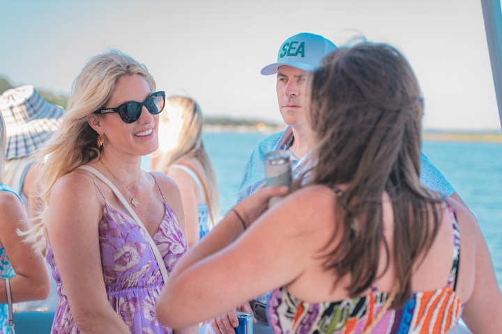 Group of people socializing on a boat under a clear sky.