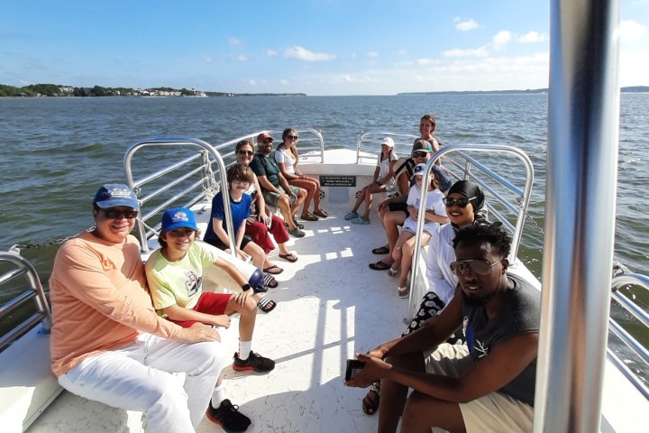 A group of people sitting on a boat under a clear blue sky.