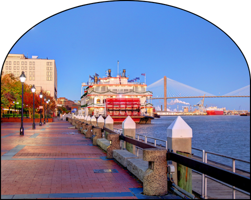 Riverfront with riverboat and suspension bridge at sunrise, cobblestone walkway, and lampposts.