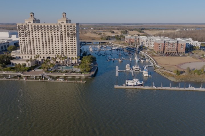 Aerial view of waterfront hotel and marina with boats docked.