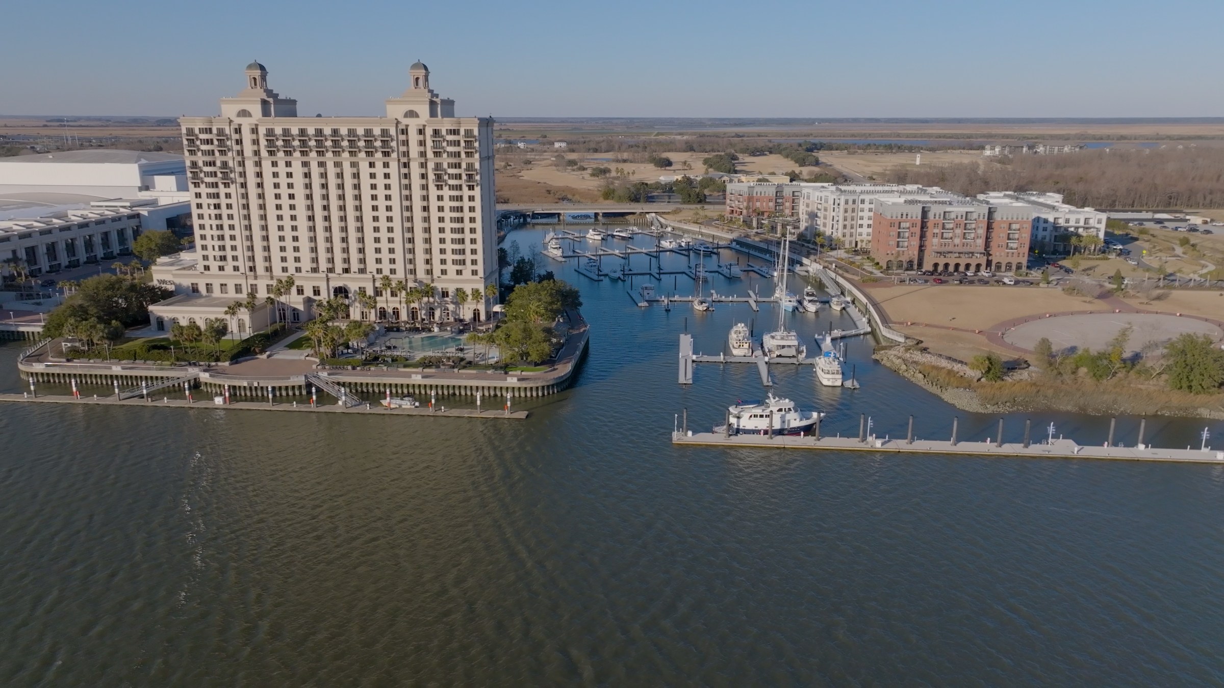 Aerial view of waterfront hotel and marina with boats docked.