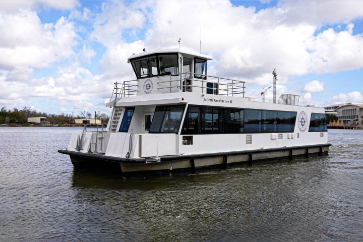 White ferry boat on a river with a cloudy sky background.