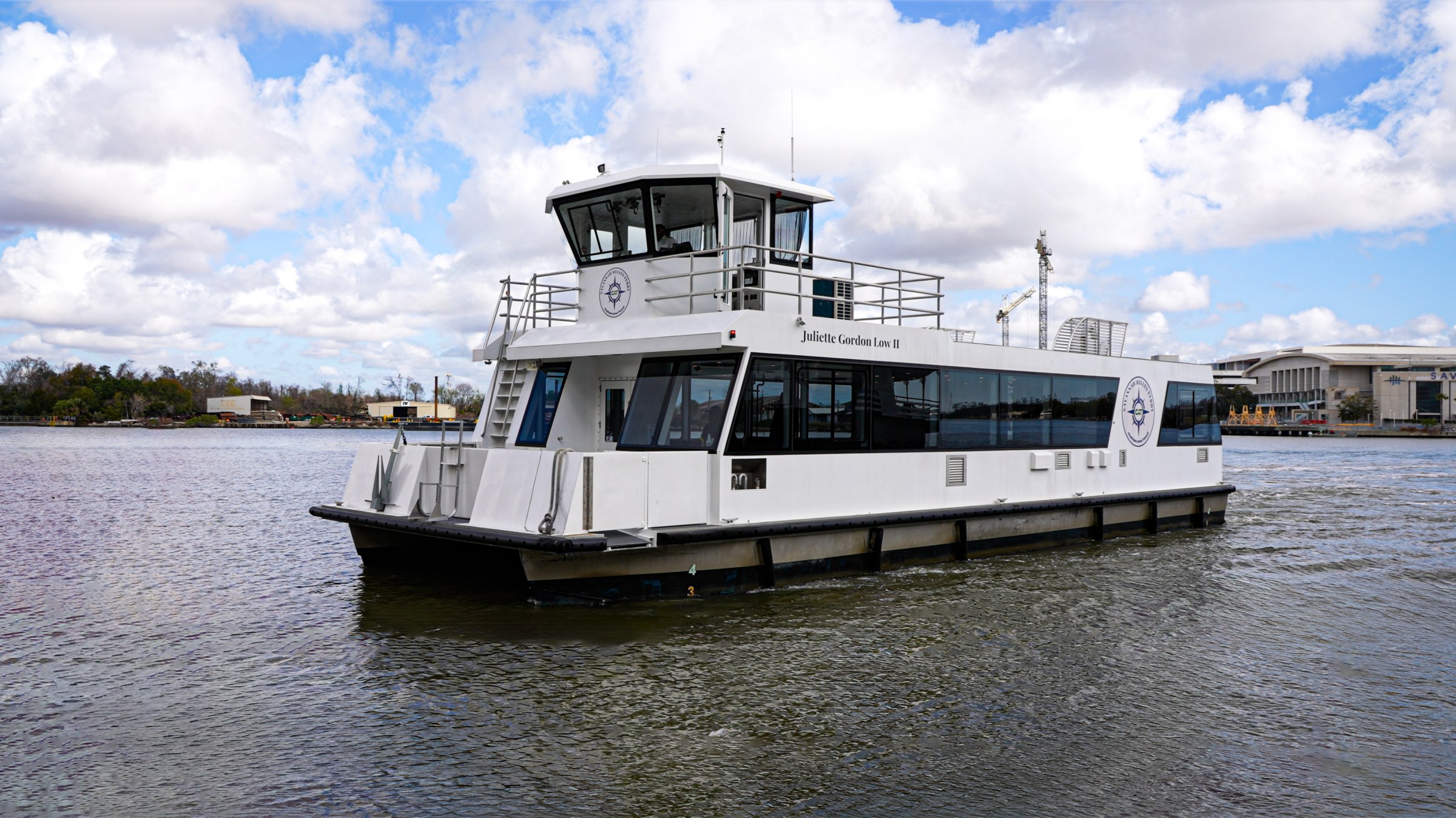 White ferry boat on a river with a cloudy sky background.